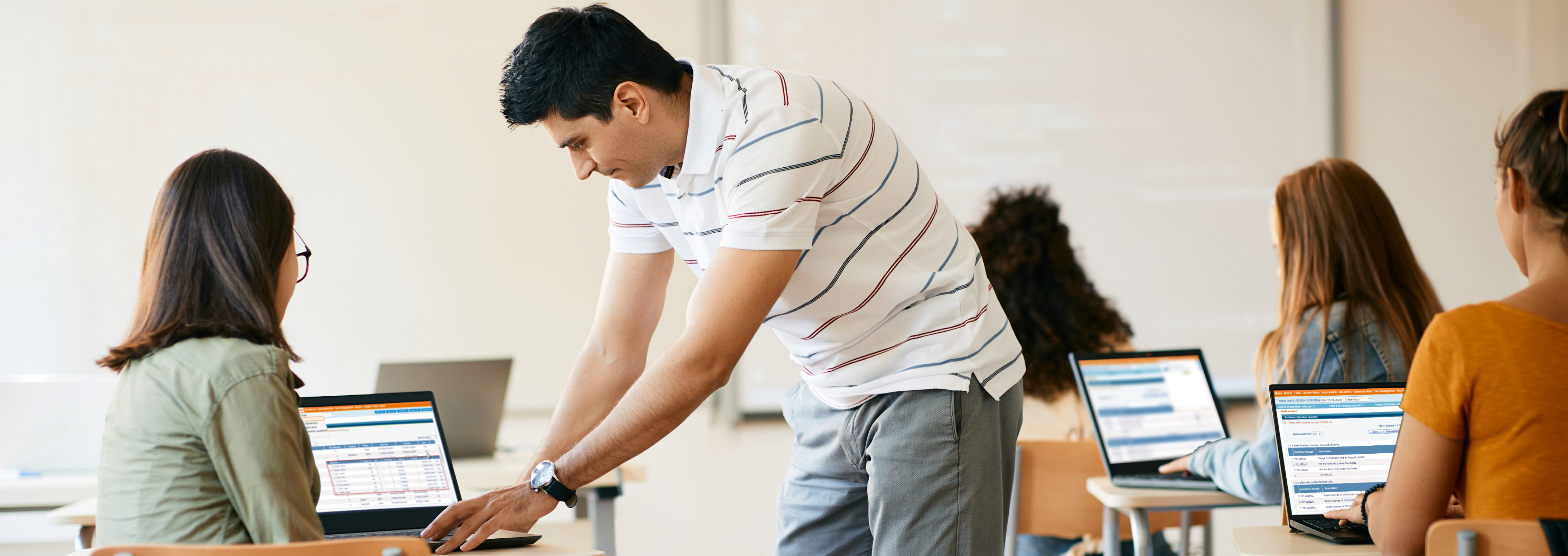 Classroom scene with teacher and student, focused on laptop display